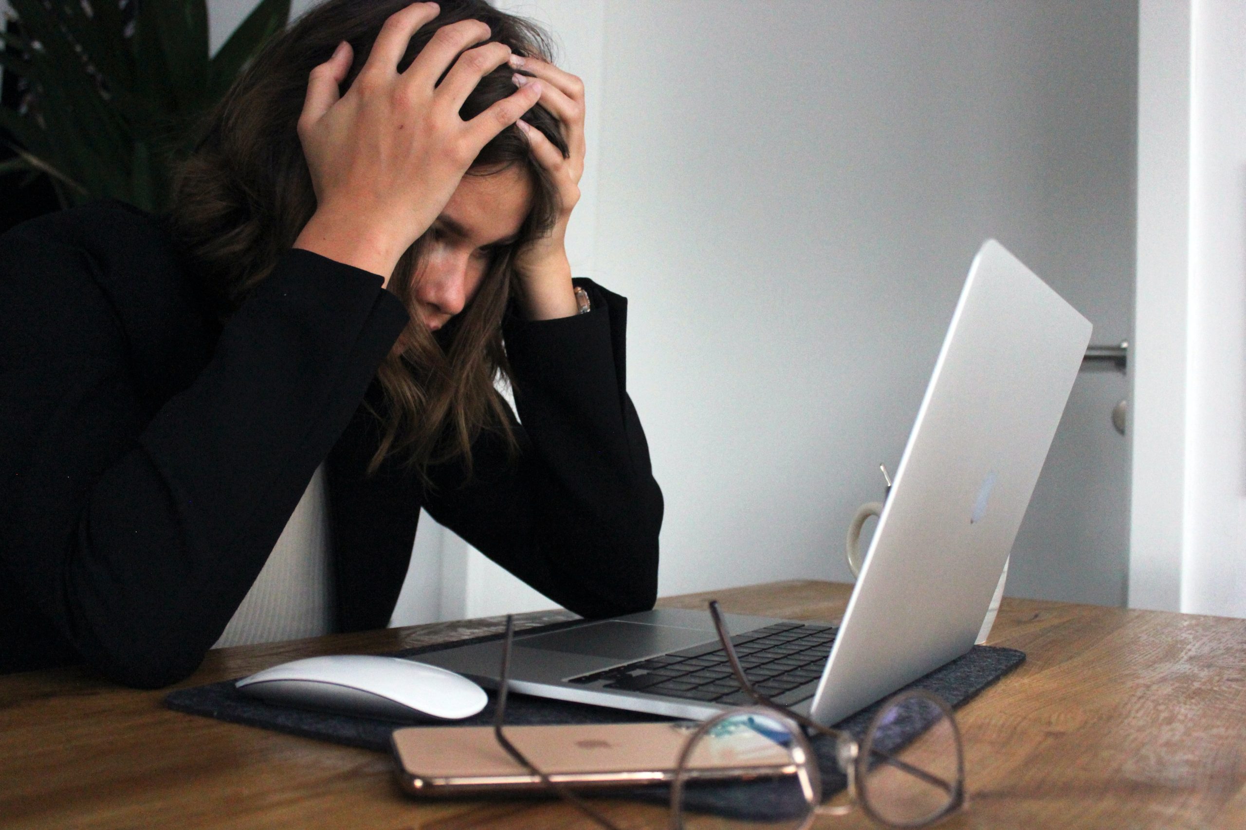 Older female student with hands on head staring at computer.