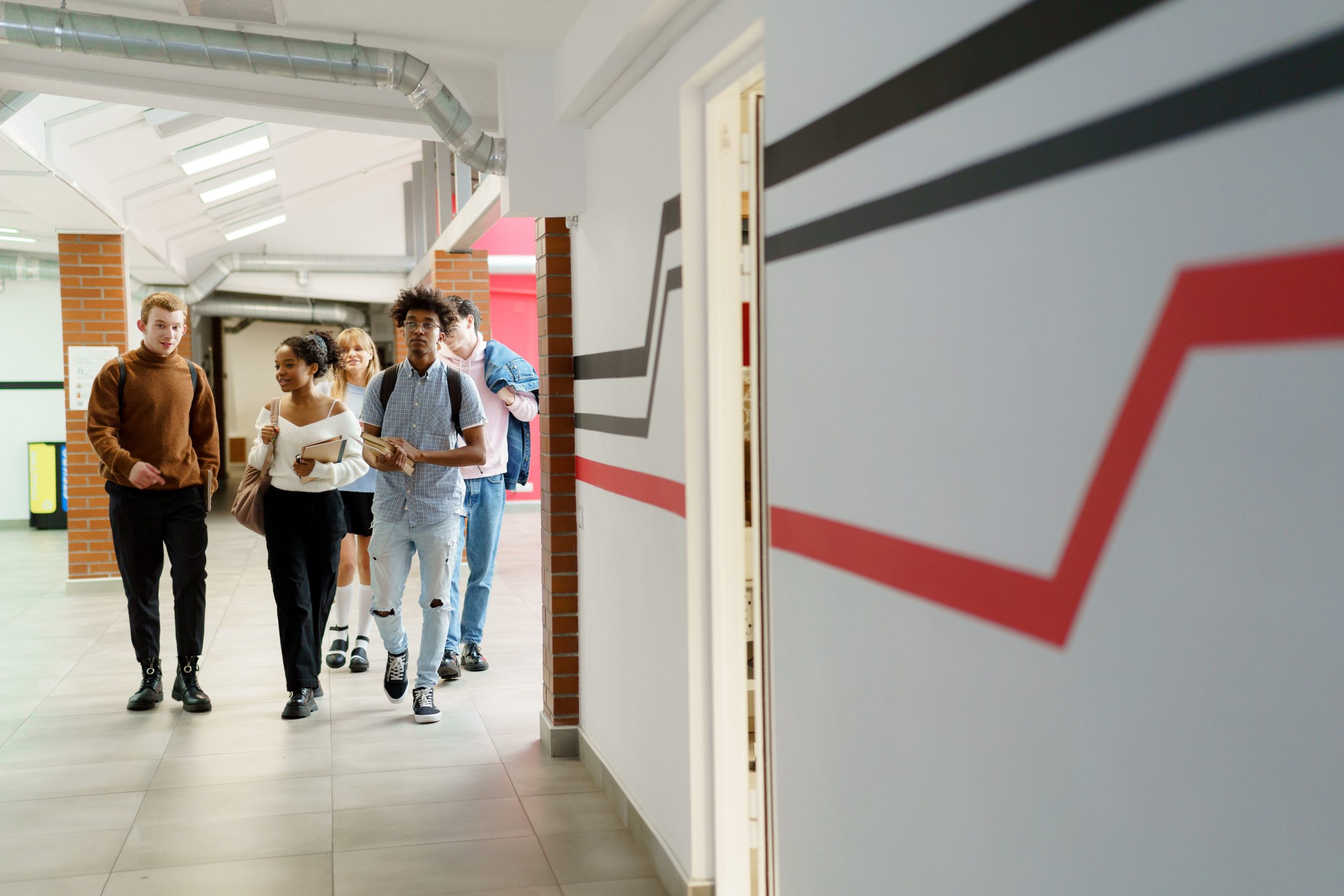 Diverse group of older students walking down school hallway.